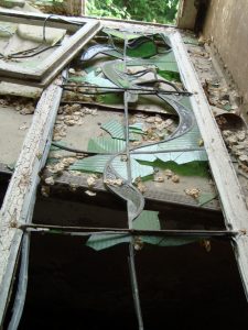 Durch Vandalismus zerstörtes historisches Glasfenster.