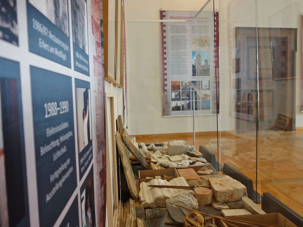 Im Vordergrund archäologische Funde, Steine, im Hintergrund Ausstellungsbanner